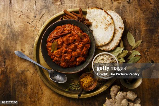 chicken tikka masala spicy curry meat food in copper pan with rice and naan bread on wooden background - tikka masala stockfoto's en -beelden