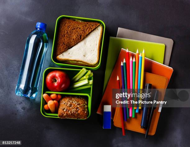 take out food lunch box with sandwiches and vegetables, bottle of water and school supplies - slate pencil stockfoto's en -beelden