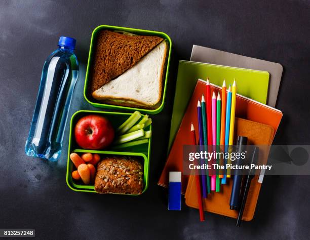 take out food lunch box with sandwiches and vegetables, bottle of water and school supplies - packed lunch - fotografias e filmes do acervo