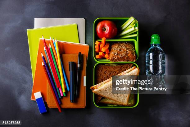 take out food lunch box with sandwiches and vegetables, bottle of water and school supplies - packed lunch - fotografias e filmes do acervo