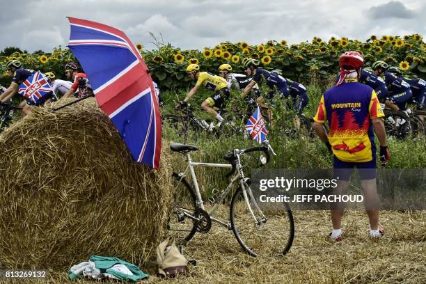 Great Britain's Christopher Froome , wearing the overall leader's yellow jersey, rides past a supporter cheering along the road next to UK Union Jack...