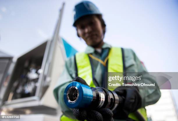Worker holds a hydrogen fuel pump nozzle as he demonstrates refueling a hydrogen powered fuel cell forklift at the Kirin Brewery Co. Plant during a...