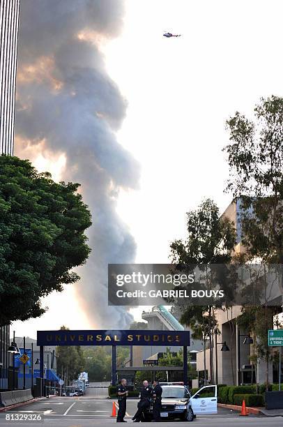 Helicopter flies over burning structures at Universal Studios, in Universal City, California, on June 01, 2008. MOre than 100 firefighters were...