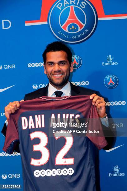 Paris Saint Germain's new Brazilian defender Dani Alves poses with his jersey as he gives a press conference on July 12 in Paris. Alves has signed a...