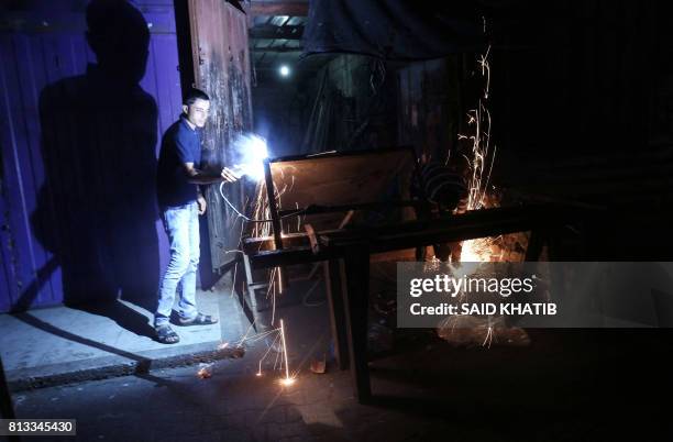 Palestinian man works at a metal workshop during the few hours of electricity supply the residents of the Gaza Strip receive per day, on July 11 at...