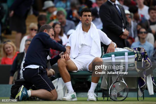 Novak Djokovic of Serbia is given treatment during the Gentlemen's Singles quarter final match against Tomas Berdych of The Czech Republic on day...