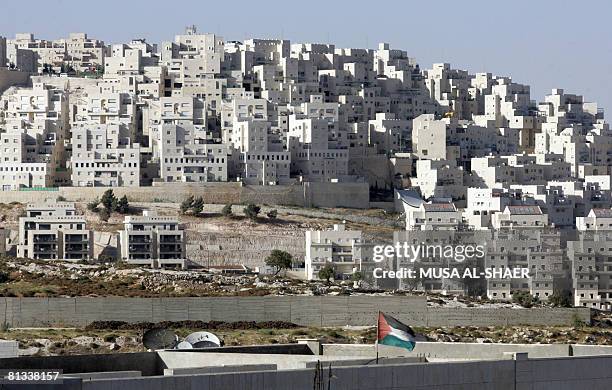 Backdropped by the Jewish settlement of Har Homa in east Jerusalem, a Palestinian flag flutters in the West Bank town of Bethlehem on June 2, 2008....