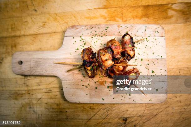 italian bacon wrapped dates appetizer on a rustic cutting board - date fruit stock pictures, royalty-free photos & images