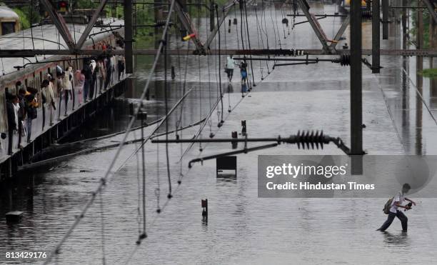 Boy walk through flooded railway track due to heavy rain and disrupted rain traffic at Kurla in Mumbai on Monday.