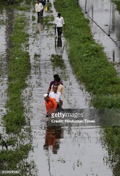 People walk through flooded railway track due to heavy rain and disrupted rain traffic at Kurla in Mumbai on Monday.