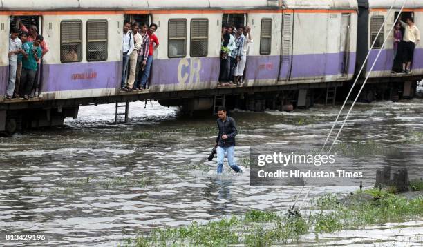 People walk through flooded railway track due to heavy rain and disrupted rain traffic at Kurla in Mumbai on Monday.