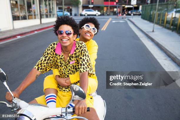 young couple riding a scooter - young man in attitude stock-fotos und bilder