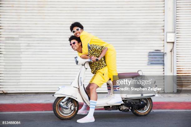 a hip young couple on a scooter - fun stockfoto's en -beelden
