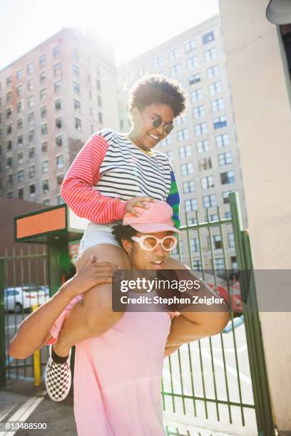 young woman riding on the shoulders of her boyfriend - colored sunglasses stockfoto's en -beelden