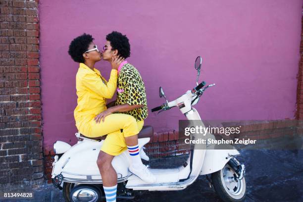 young couple kissing on the back of a scooter - black couples kissing stock pictures, royalty-free photos & images