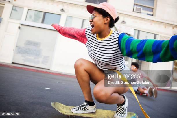young woman skateboarding - junger erwachsener stock-fotos und bilder