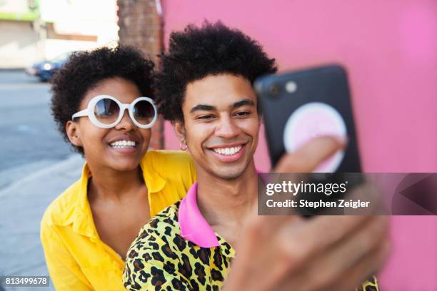 young couple taking a selfie - colored sunglasses stockfoto's en -beelden