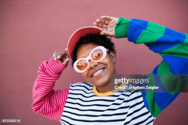 portrait of young woman wearing sunglasses - colored clothes stock-fotos und bilder