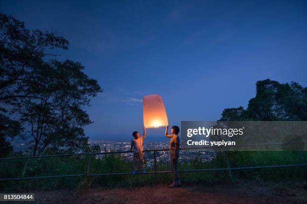 moeder en zoon hemel lantaarn vliegen bij nacht - loi krathong stockfoto's en -beelden