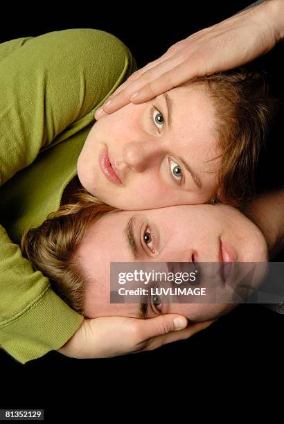 double portait of boy and girl, with hands holding each others face. - double facepalm stock pictures, royalty-free photos & images