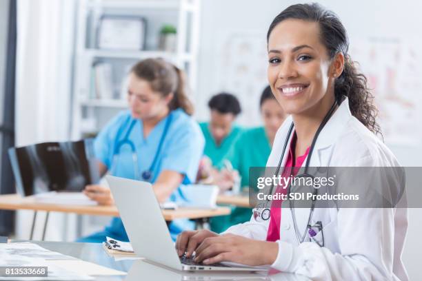 fröhliche medizinische intern verwendet einen laptop im klassenzimmer - medical study stock-fotos und bilder