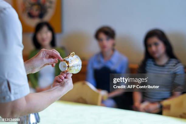 Teacher shows a cup during a lesson at the Switzerland's last finishing school Institut Villa Pierrefeu on June 26, 2017 in Glion. Eight women sit...