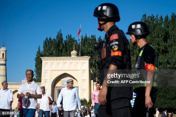 This picture taken on June 26, 2017 shows police patrolling as Muslims leave the Id Kah Mosque after the morning prayer on Eid al-Fitr in the old...
