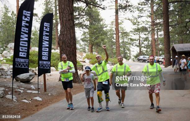 Adam Connor of Australia walks to the finish line with his support crew and his son, Alex, during the STYR Labs Badwater 135 on July 12, 2017 in...
