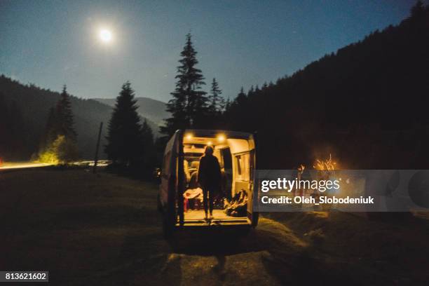 Silhouette of woman standing in the van at night near the camping