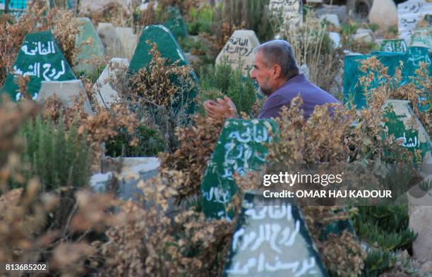 Syrian man prays on July 12, 2017 at a cemetary in Khan Sheikhun, a rebel-held town in the northwestern Syrian Idlib province, 100 days following a...