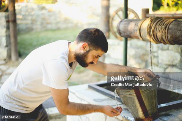 jonge man goed drinkwater uit trekken - waterput stockfoto's en -beelden