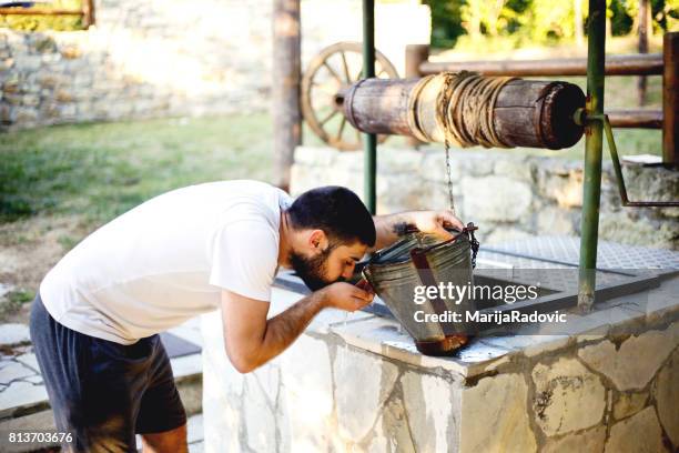 jonge man goed drinkwater uit trekken - waterput stockfoto's en -beelden