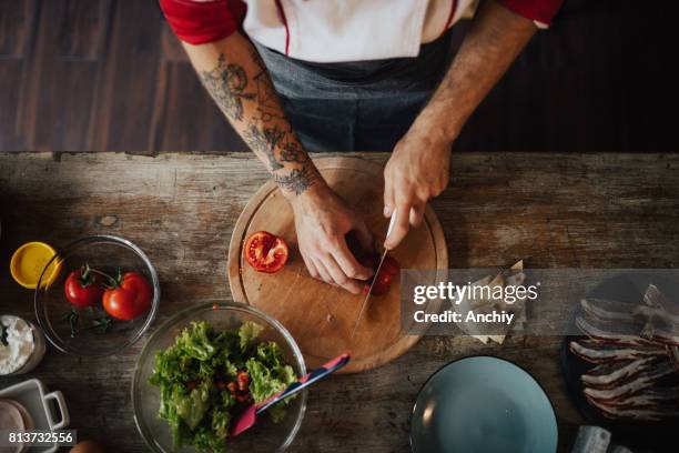 unser chef schöpft das messer scheibe tomate in kleinere stücke für salat - hacken essenszubereitung stock-fotos und bilder