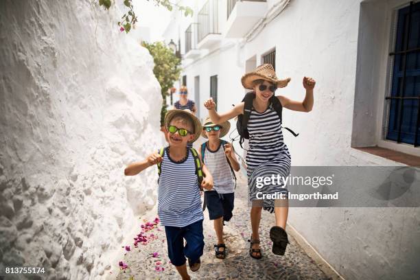 familia feliz correr en la calle en pueblo andaluz blanco - casa real española fotografías e imágenes de stock