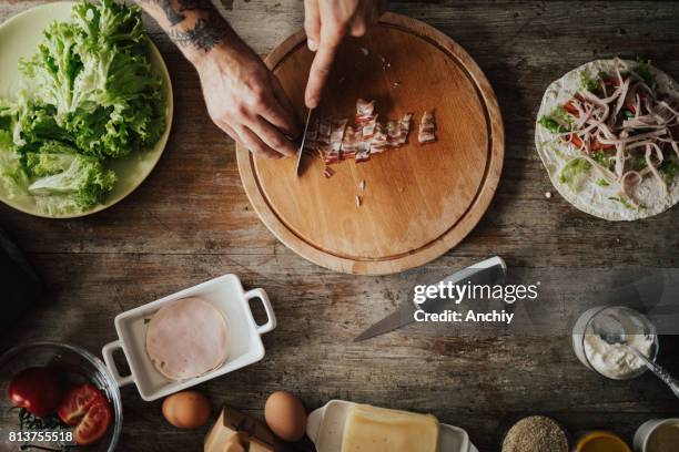 eine person ist hacken speck für wrap-sandwich - brotzeitbrett stock-fotos und bilder