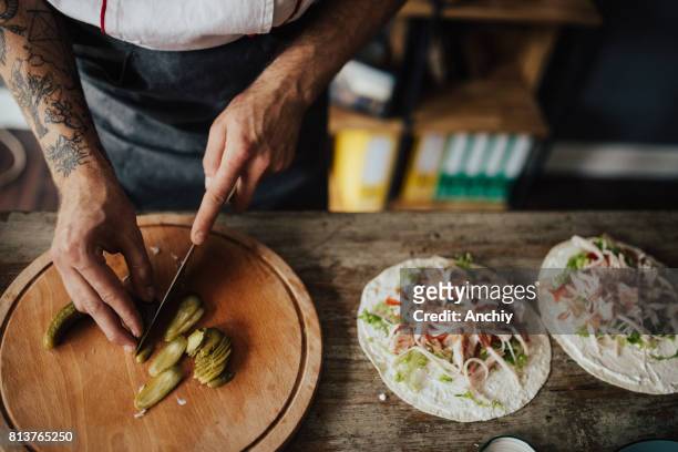 chef-kok snijdt picles in dunne plakjes voor wrap sandwich - making a sandwich stockfoto's en -beelden