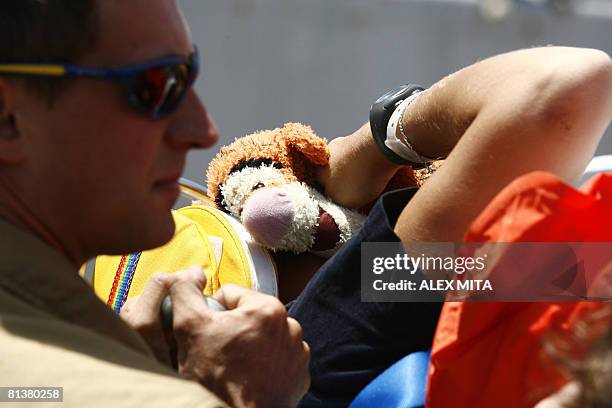 French female sailor injured in a car accident in Haifa, Israel, covers her face with a stuffed toy as her comrades transfer her from aboard the...
