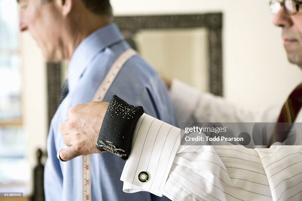 Tailor measures man's shoulders