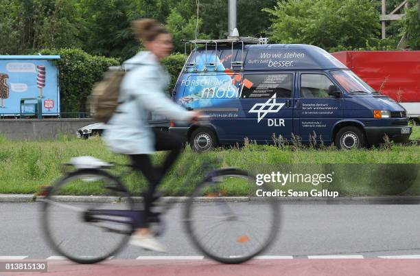 Young woman on a bicycle rides past a van of the German Aerospace Center that was conducting traffic analysis for bicycle safety on Moritzplatz...