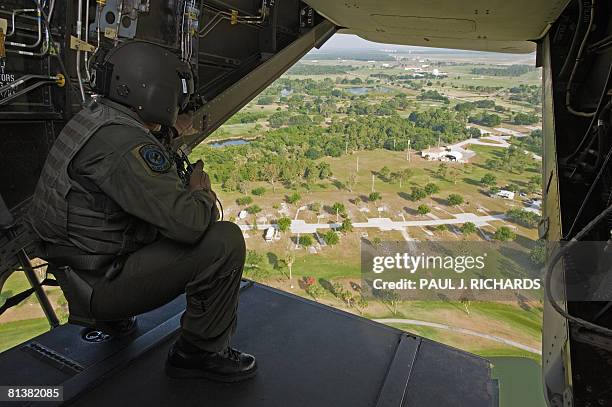 Crewman looks out the rear door of a US Air Force CV-22 Osprey tiltrotor aircraft that combines the vertical takeoff, hover and vertical landing...