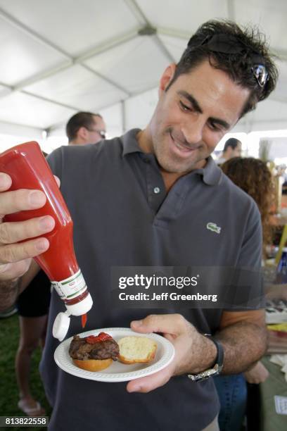 Man putting ketchup on a burger at the Great Taste of the Grove food festival.