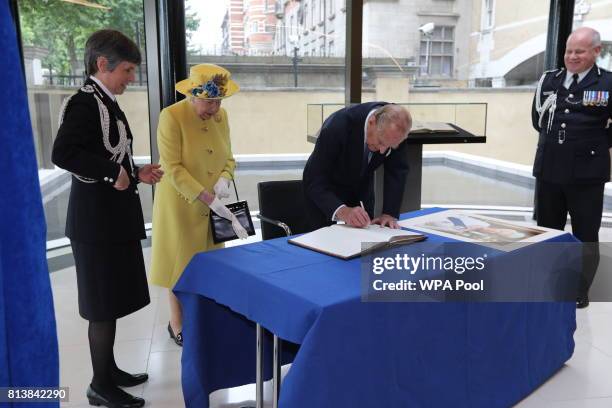 Queen Elizabeth II and Prince Philip, Duke of Edinburgh sign a book, watched by Commissioner of the Metropolitan Police Cressida Dick and Deputy...