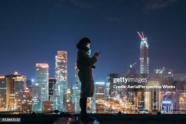 asian woman using mobile phone in downtown district - beijing skyline night stock pictures, royalty-free photos & images