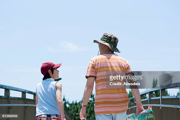 grandfather and grandson (8-9) walking on bridge, rear view, waist up - black hair back stock pictures, royalty-free photos & images