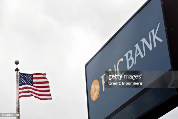An American flag flies next to PNC Financial Services Group Inc. Signage displayed outside a bank branch in Morton, Illinois, U.S., on Monday, July...
