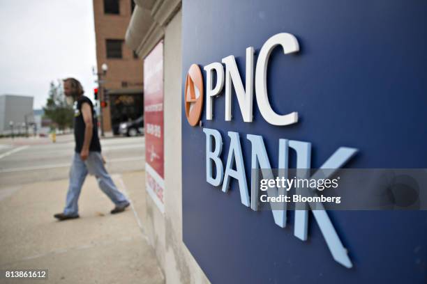 Pedestrian passes signage displayed at a PNC Financial Services Group Inc. Bank branch in Peoria, Illinois, U.S., on Monday, July 10, 2017. PNC...