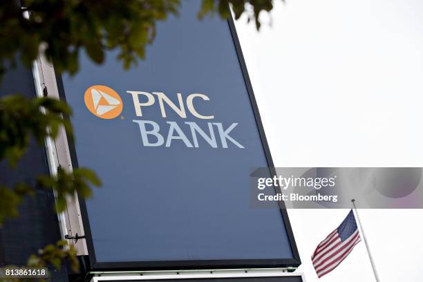 An American flag flies next to PNC Financial Services Group Inc. Signage displayed outside a bank branch in Peoria, Illinois, U.S., on Monday, July...