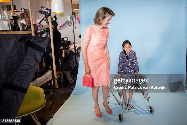 Queen Mathilde of Belgium pose with a girl during a photoshoot during her visit to the editorial rooms of Belgium's oldest women's magazines Libelle...