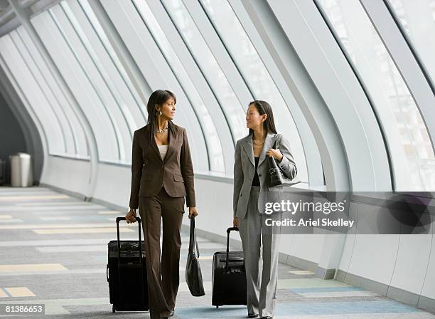 multi-ethnic businesswomen pulling suitcases - businesswoman airport stock pictures, royalty-free photos & images
