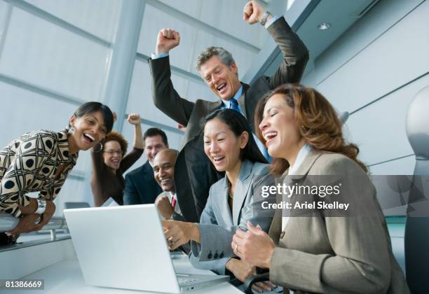 multi-ethnic businesspeople cheering at laptop - group of businesspeople standing low angle view stock pictures, royalty-free photos & images